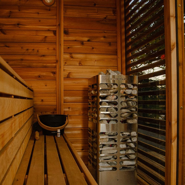 Electric sauna heater in sauna corner with stacked rocks and vented metal body