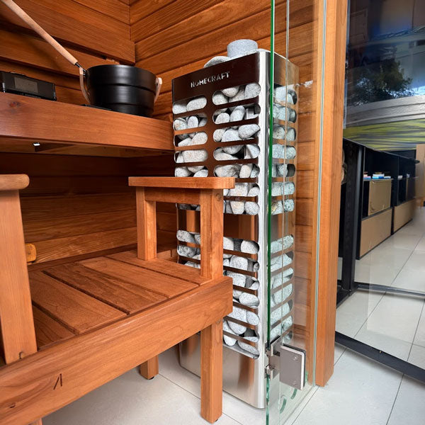 Sauna heater with stacked rocks and HOMECRAFT logo, placed near a wooden sauna bench