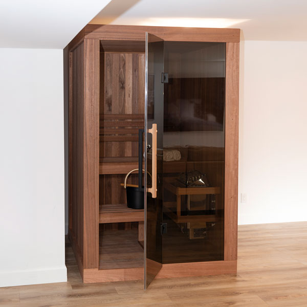 Wooden sauna with hinged glass door, interior benches visible through doorway