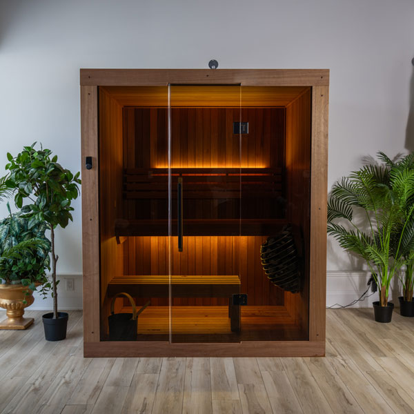Wooden studio sauna with glass door, tiered benches, and glowing overhead light strip.