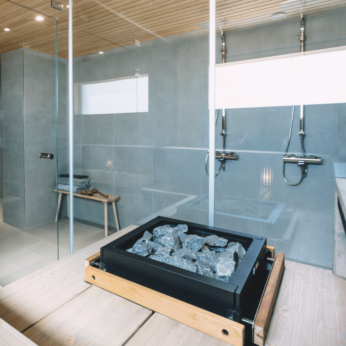 Electric sauna heater with black stone compartment and gray stones inside sauna