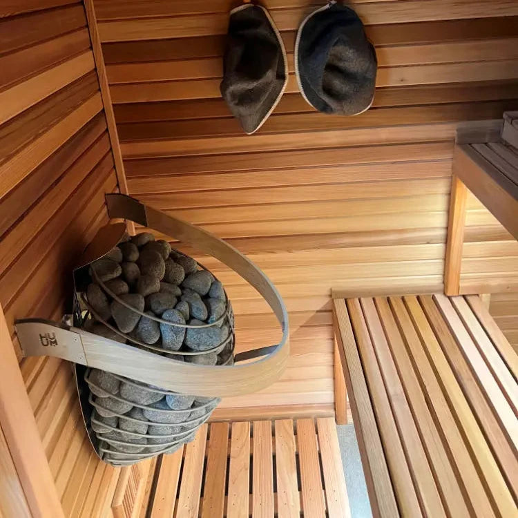 Sauna heater basket filled with grey stones near wooden benches