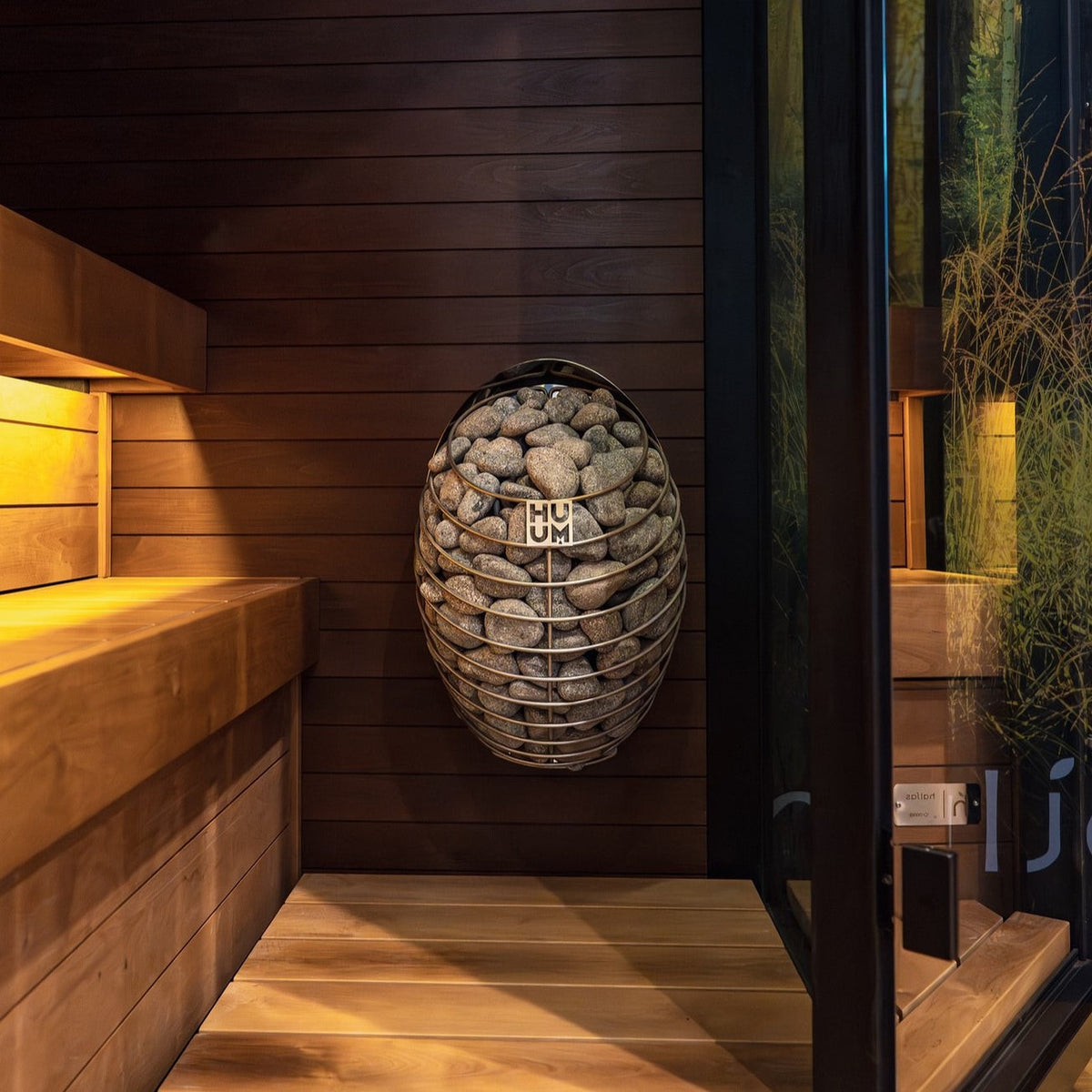 HUUM sauna heater basket filled with gray stones in a metal cage