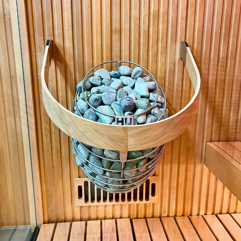 Electric sauna heater with light gray stones in circular wire basket