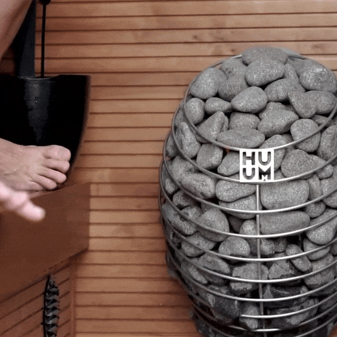 Electric sauna heater filled with gray stones in metal basket