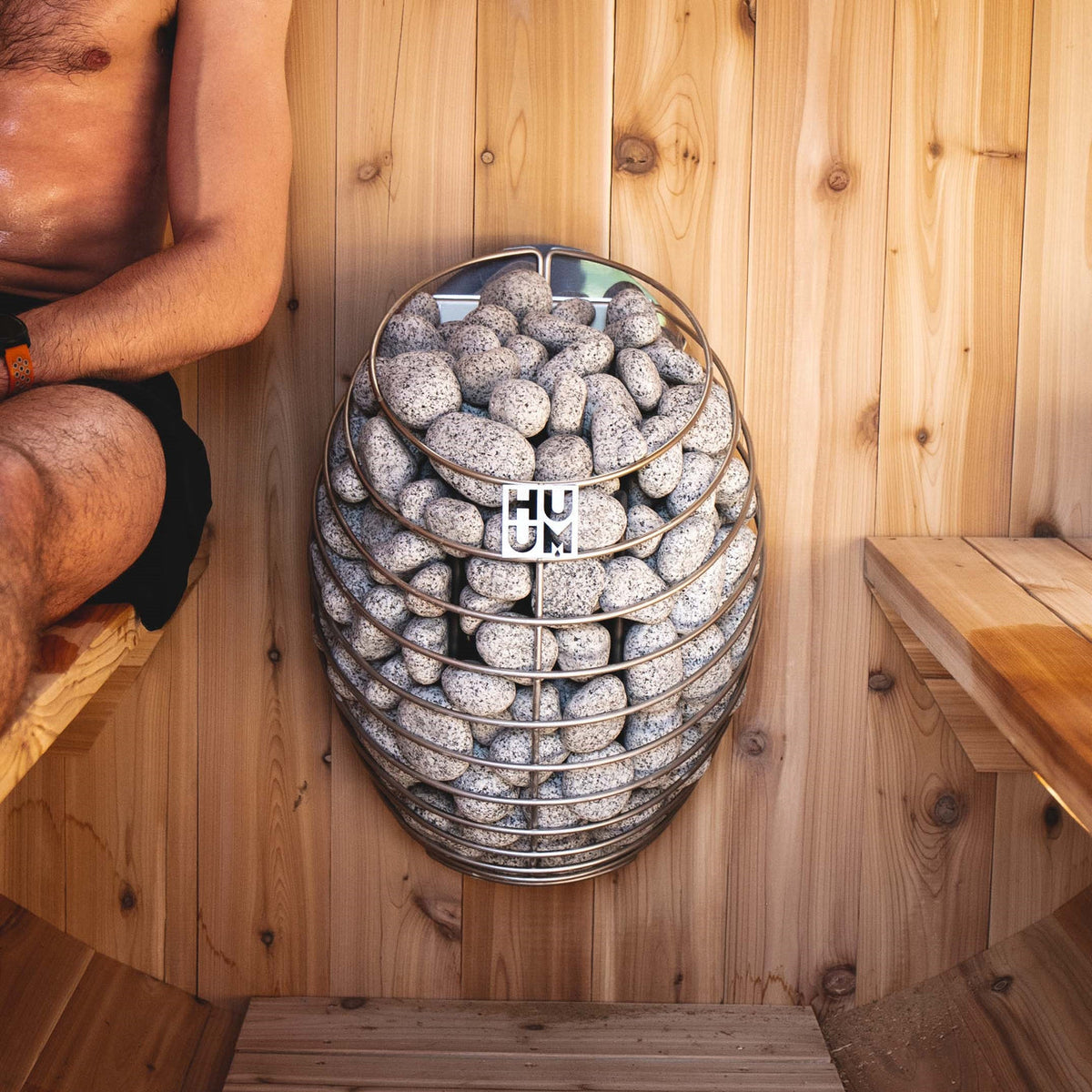 HUUM sauna heater stone basket filled with gray rocks, front view