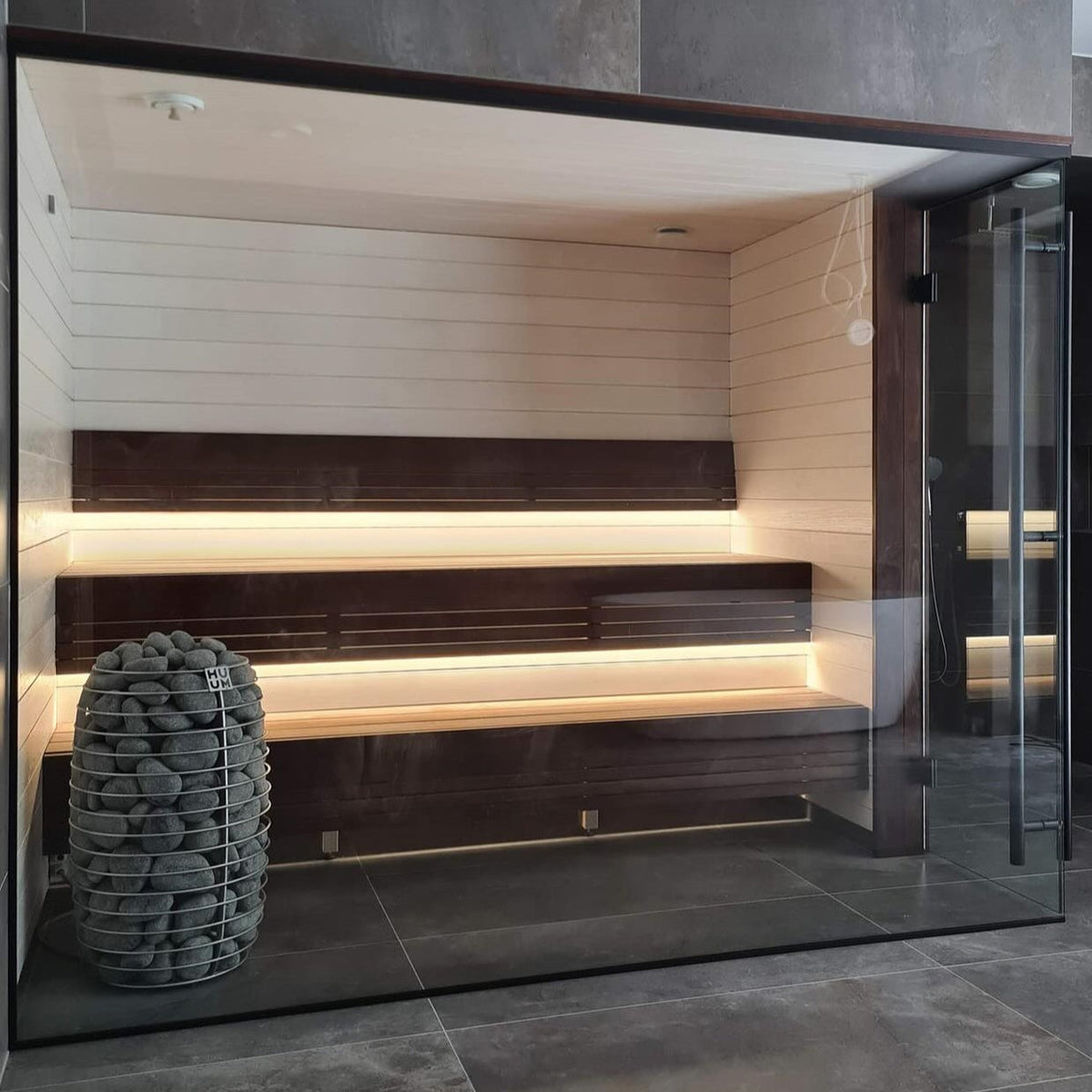Sauna heater stone cage in glass-enclosed sauna with wooden interior and benches