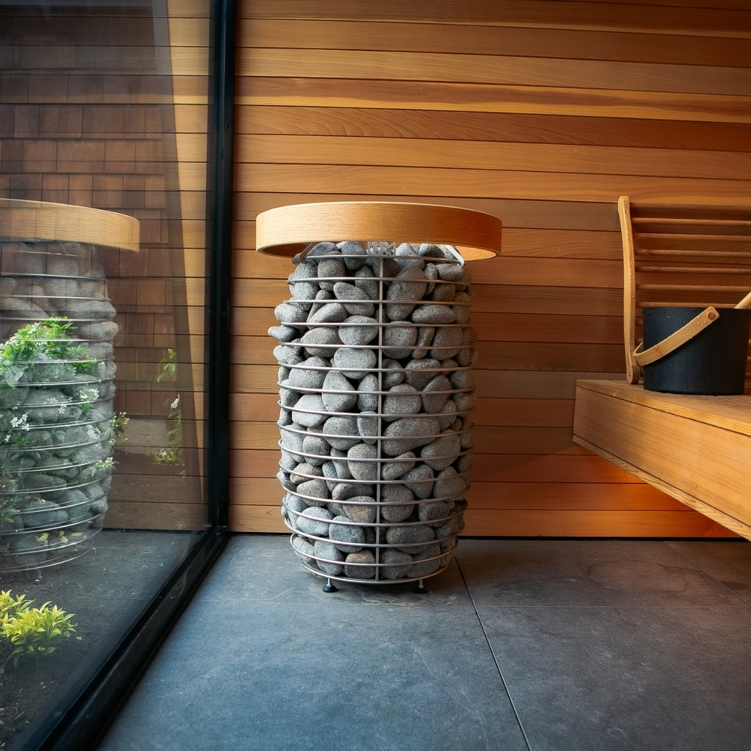 Sauna heater with stacked gray stones and light wood cover in a wooden room