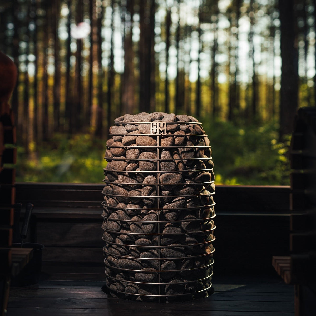 Sauna heater packed with gray stones, cylindrical metal frame with HUUM marking