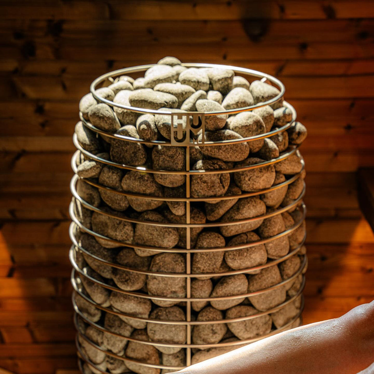 Close-up of electric sauna heater with round, light stones and wire support rings