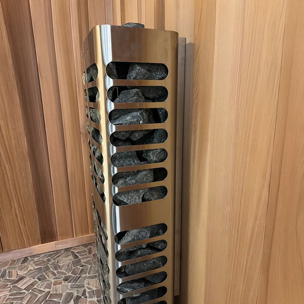 Slim sauna heater beside wood paneling, showing side stones and vented stainless casing
