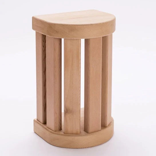 A small wooden stool with a rounded triangular seat and four vertical slats dundalk luescraft sauna