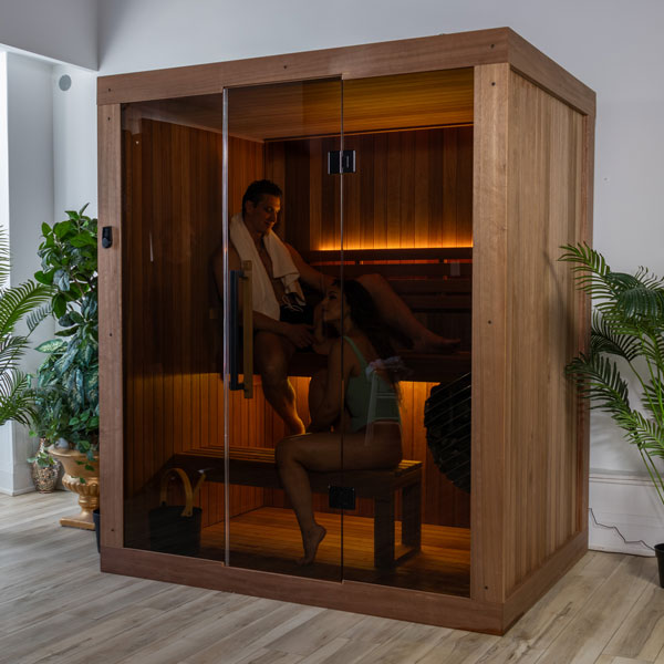 Wood sauna with glass door and two people relaxing inside on the bench
