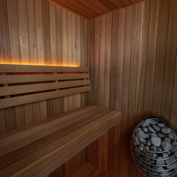 Interior wood sauna with wall bench and bucket-style heater filled with stones