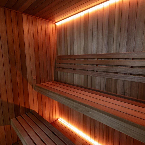 Sauna interior corner with stacked benches and glowing light strip along the lower step.