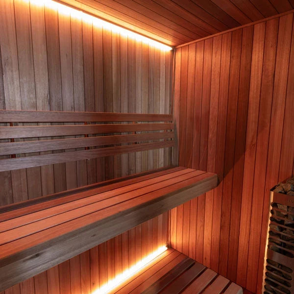Wood sauna benches with warm under-seat lighting and vertical panel walls inside the sauna.