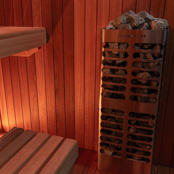 Sauna heater with rock basket labeled HOMECRAFT beside wooden bench and wall panels.
