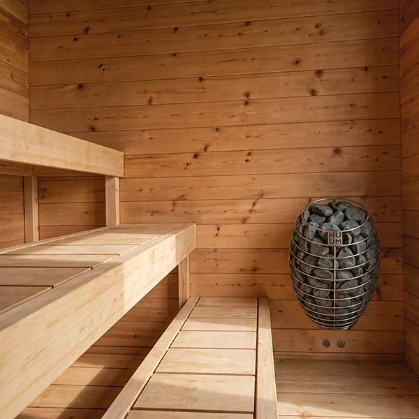 Wood sauna interior with bench seating and round rock heater stove