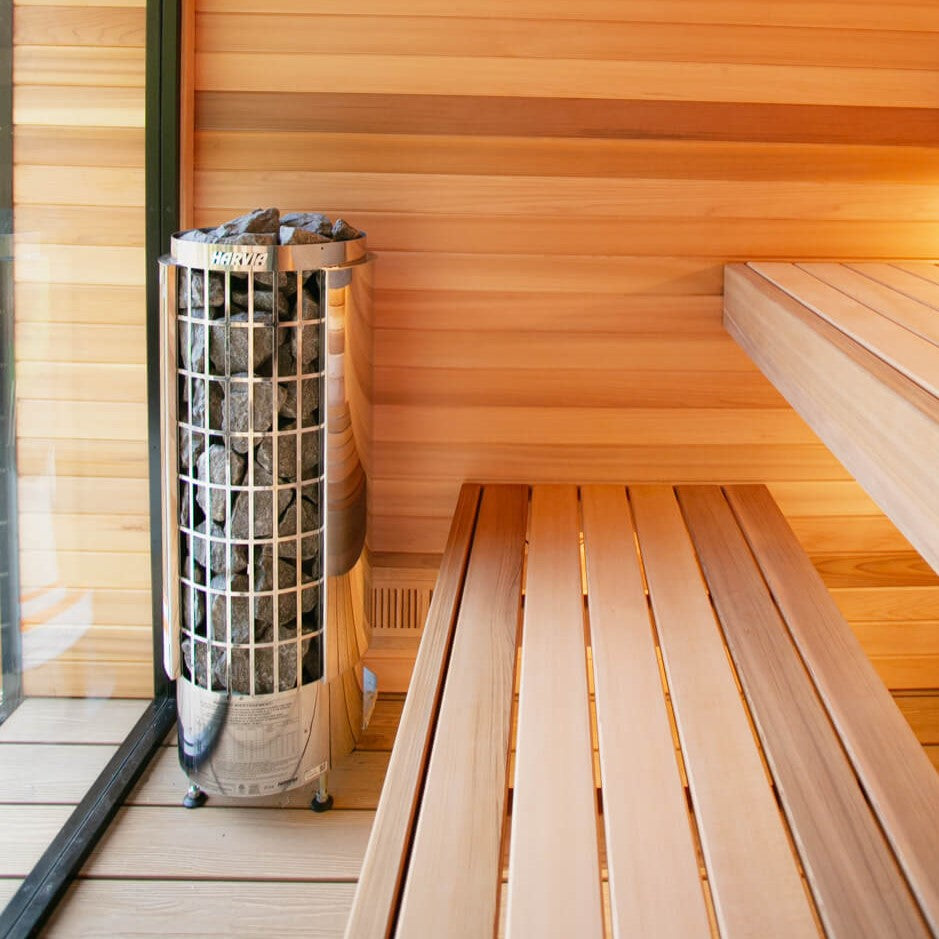 Harvia sauna heater beside wooden benches in a light wood sauna