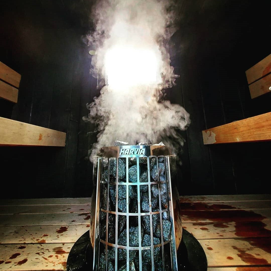Sauna heater with steam rising from the stone basket during operation