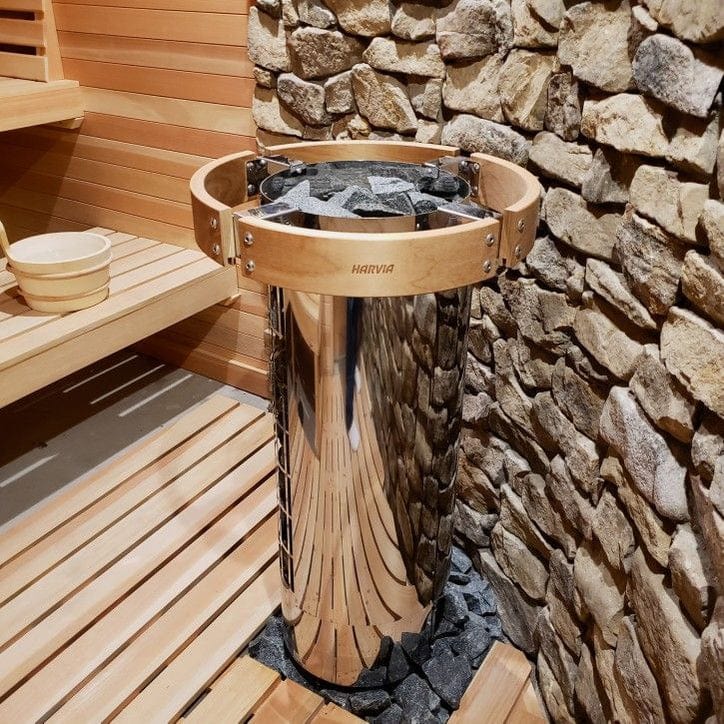 Stainless sauna heater cylinder surrounded by stones with metal rim and guard
