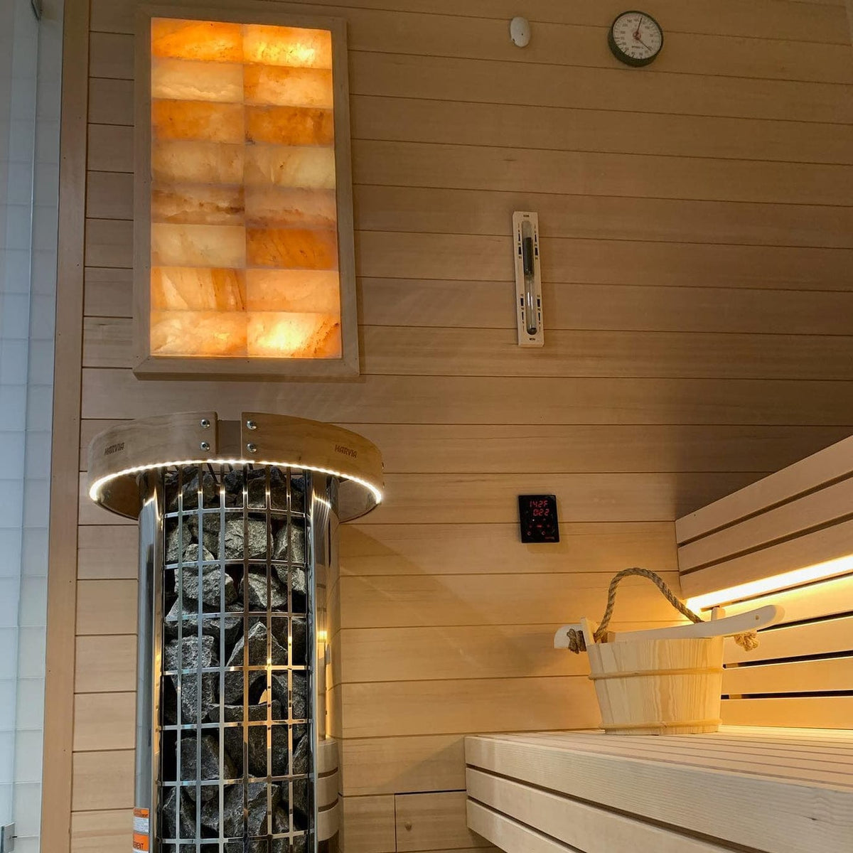 Round sauna heater top with stone-filled interior and attached control display