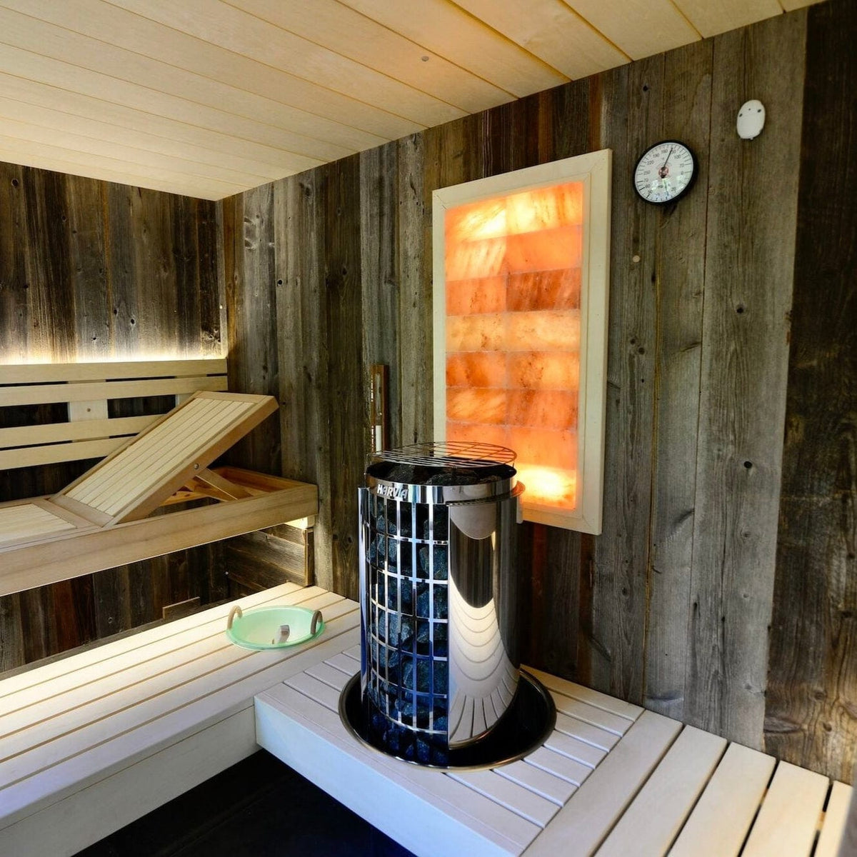 Sauna heater stove with glowing interior flame through rocks in gray stone sauna room