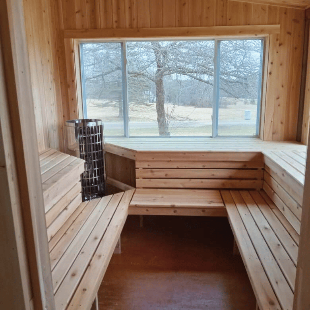 Wood sauna with bench seating and cylindrical sauna heater near the wall