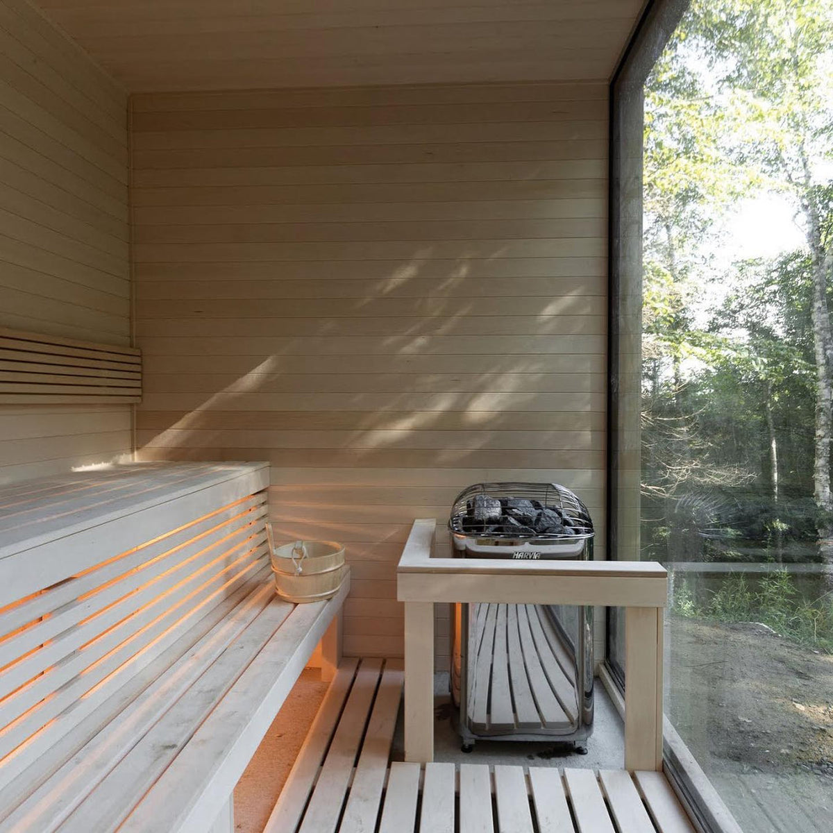 Electric sauna heater with stone rocks and a small heat box on a wooden sauna floor