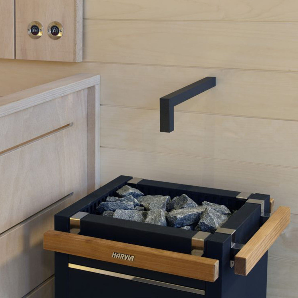 Corner sauna heater with black stone tray and wooden guard, filled with grey rocks