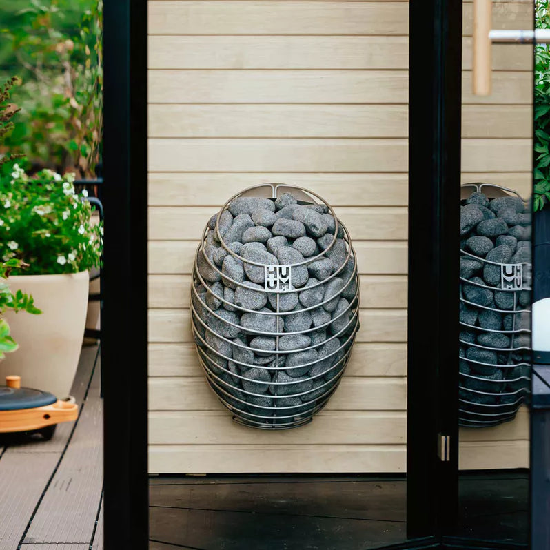 Round sauna heater packed with grey stones with HUUM logo label