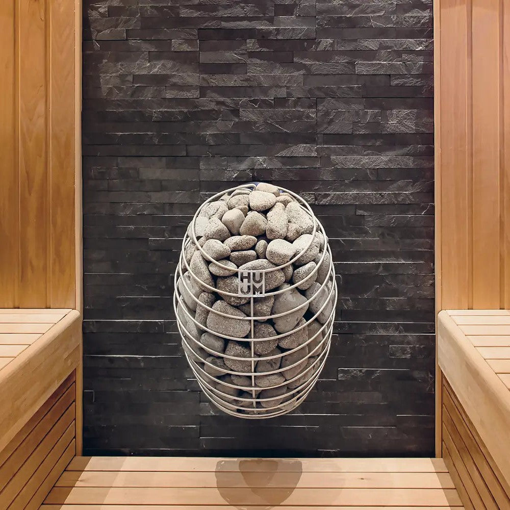 HUUM sauna heater with gray stone basket against black stone wall