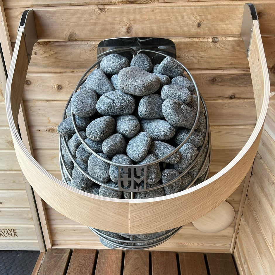 HUUM sauna heater with gray stone basket, stones piled close-up
