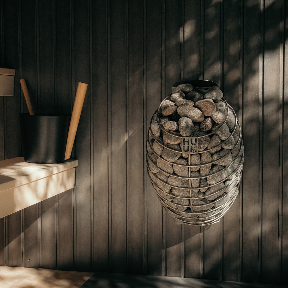 HUUM electric sauna heater with gray stones in wire ring basket