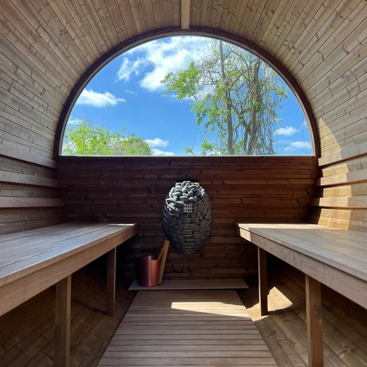 HUUM sauna heater with stone basket centered between wooden benches