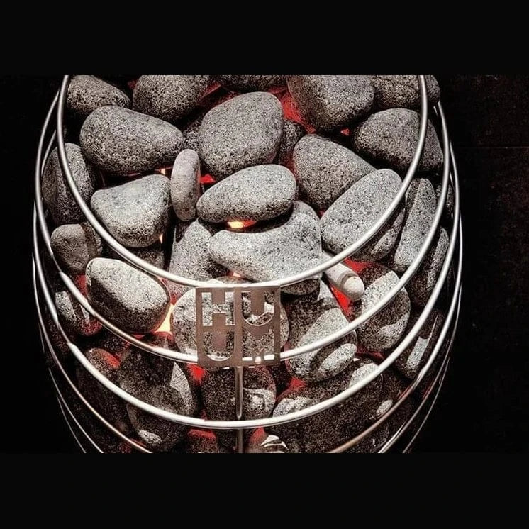 Electric sauna heater with gray stones and glowing red heating elements
