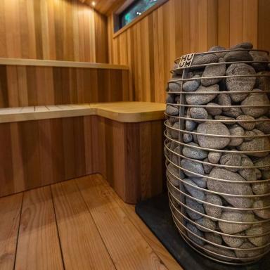 Electric sauna heater with stacked gray stones in round metal cage