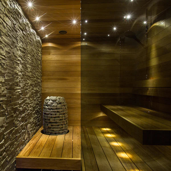 Wood sauna corner with tall stone heater on floor beside wooden bench seating