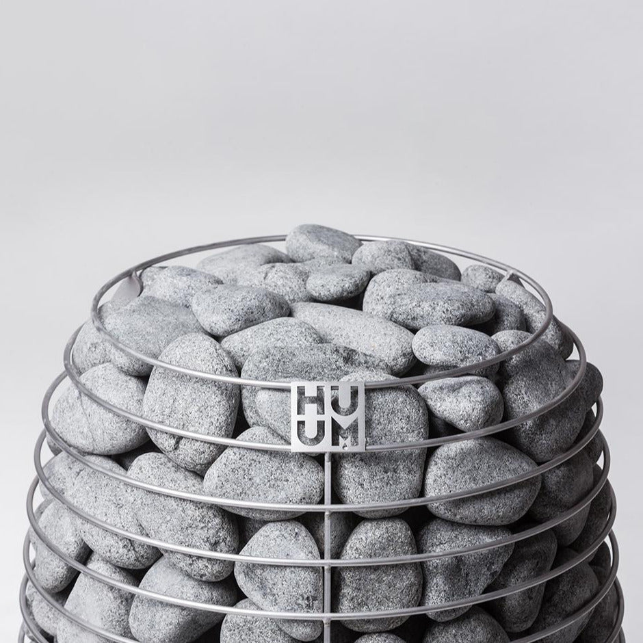 Gray sauna stones packed in metal heater ring with HUUM badge