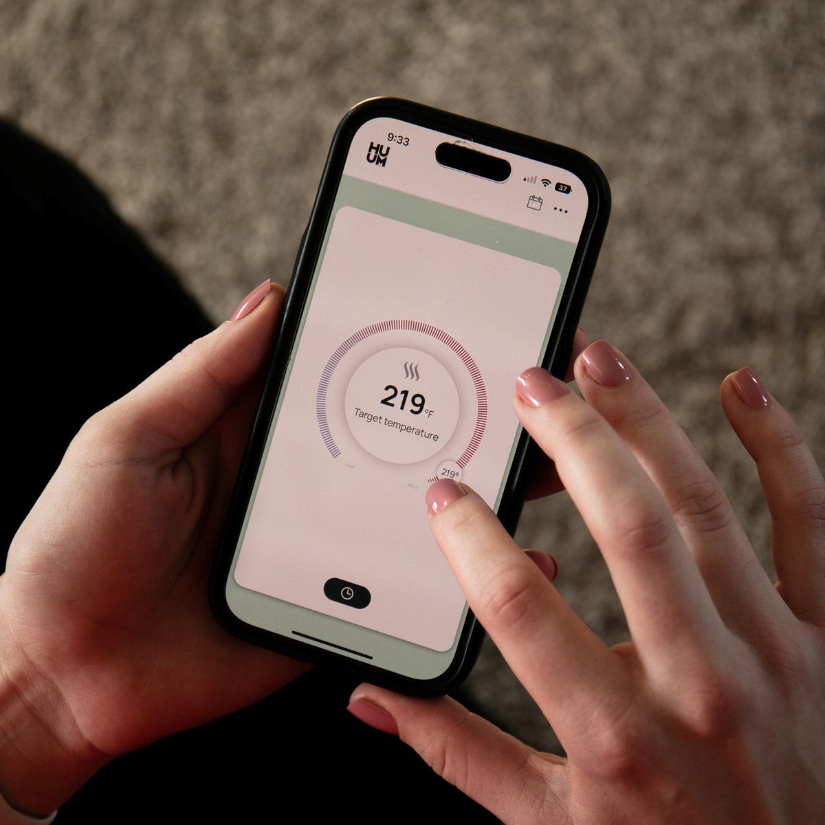 Hand holding a smartphone showing sauna heater temperature control interface