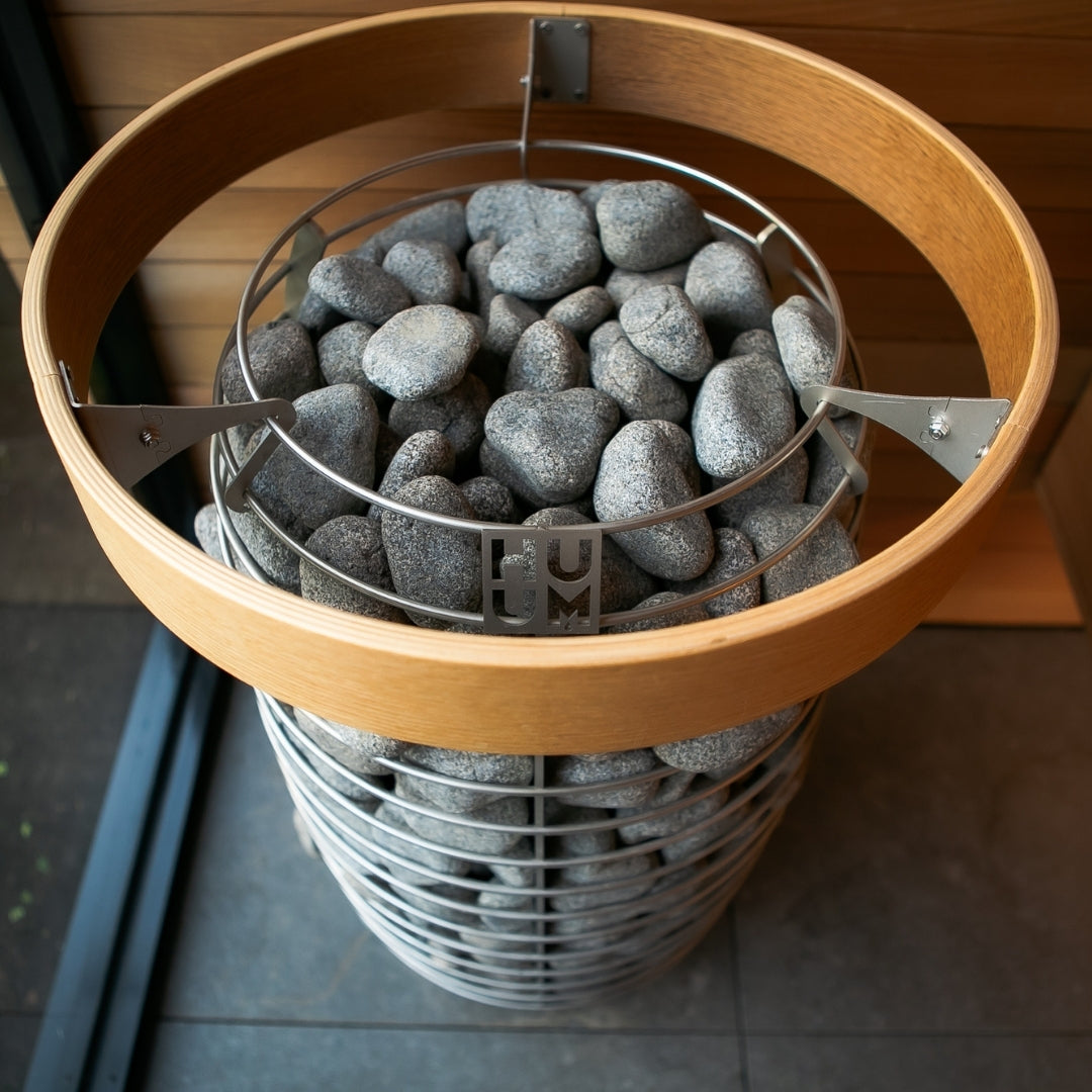 Electric sauna heater top view with gray stones and HUUM marker on the rim