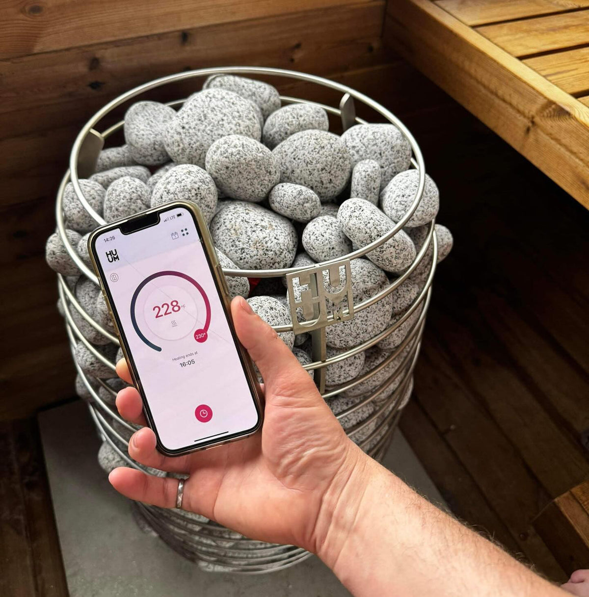 Sauna heater stone basket with hand using HUUM control phone app