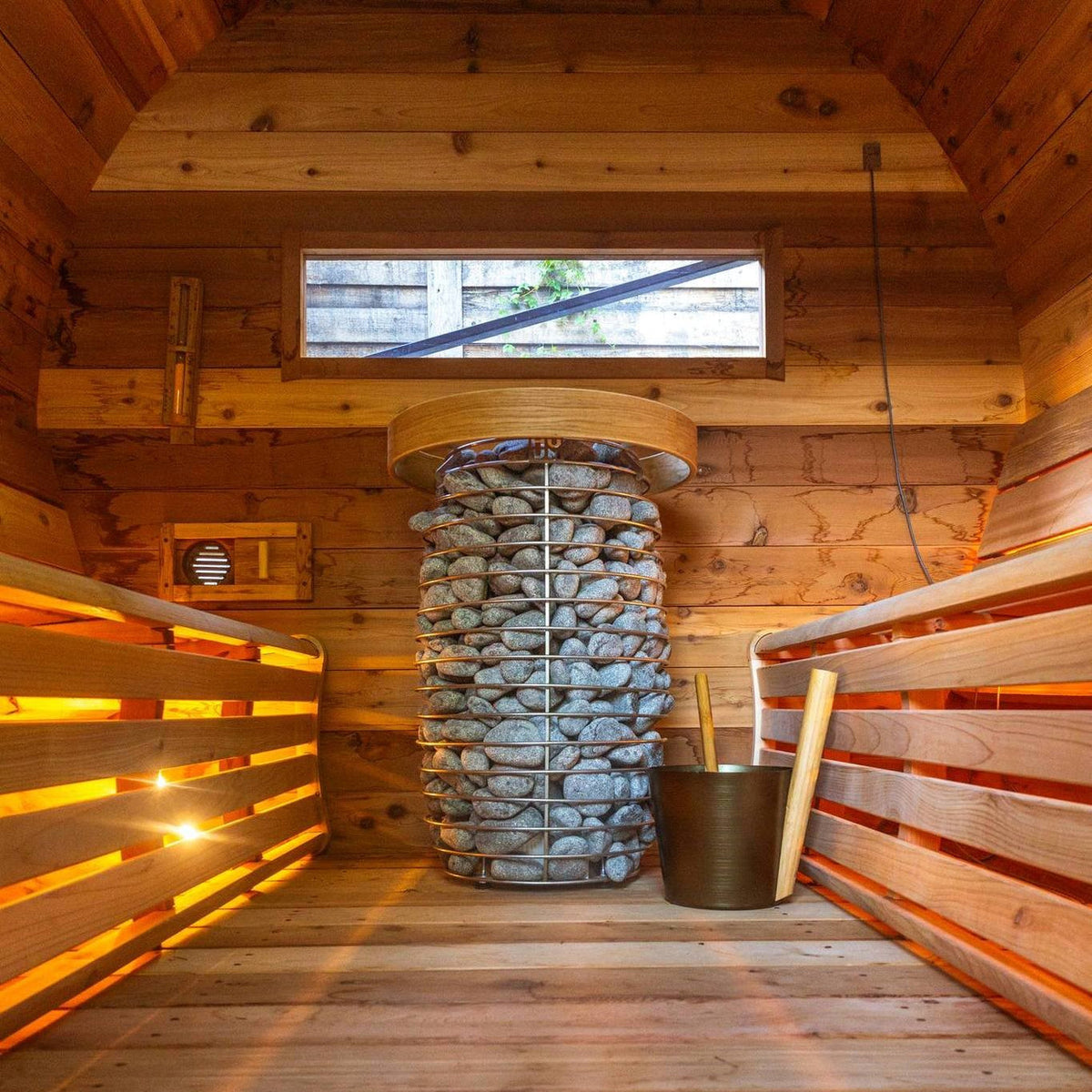 Wooden sauna interior with electric heater packed with gray stones in the center