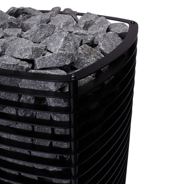 Black barrel wood-burning sauna heater with gray rocks in the upper stone basket